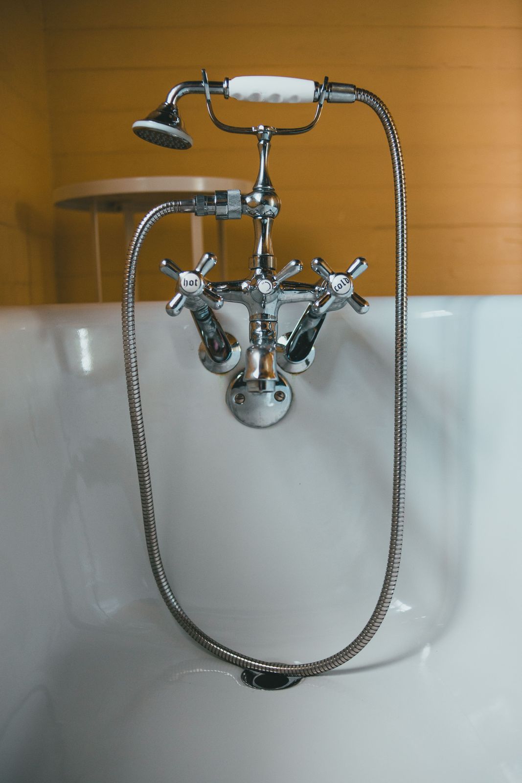 Chrome telephone-style bath mixer with hot and cold cross handles, white handset and long metal hose